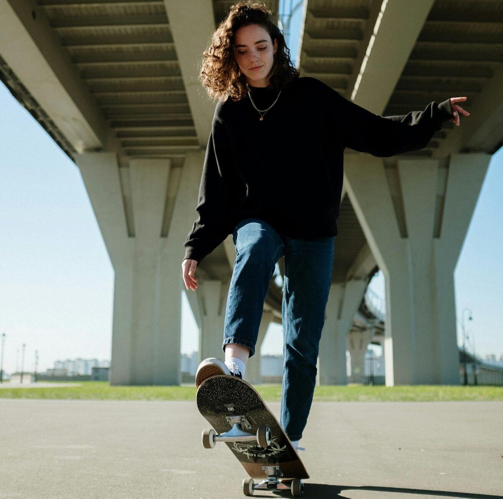 girl skate boarding under a bridge