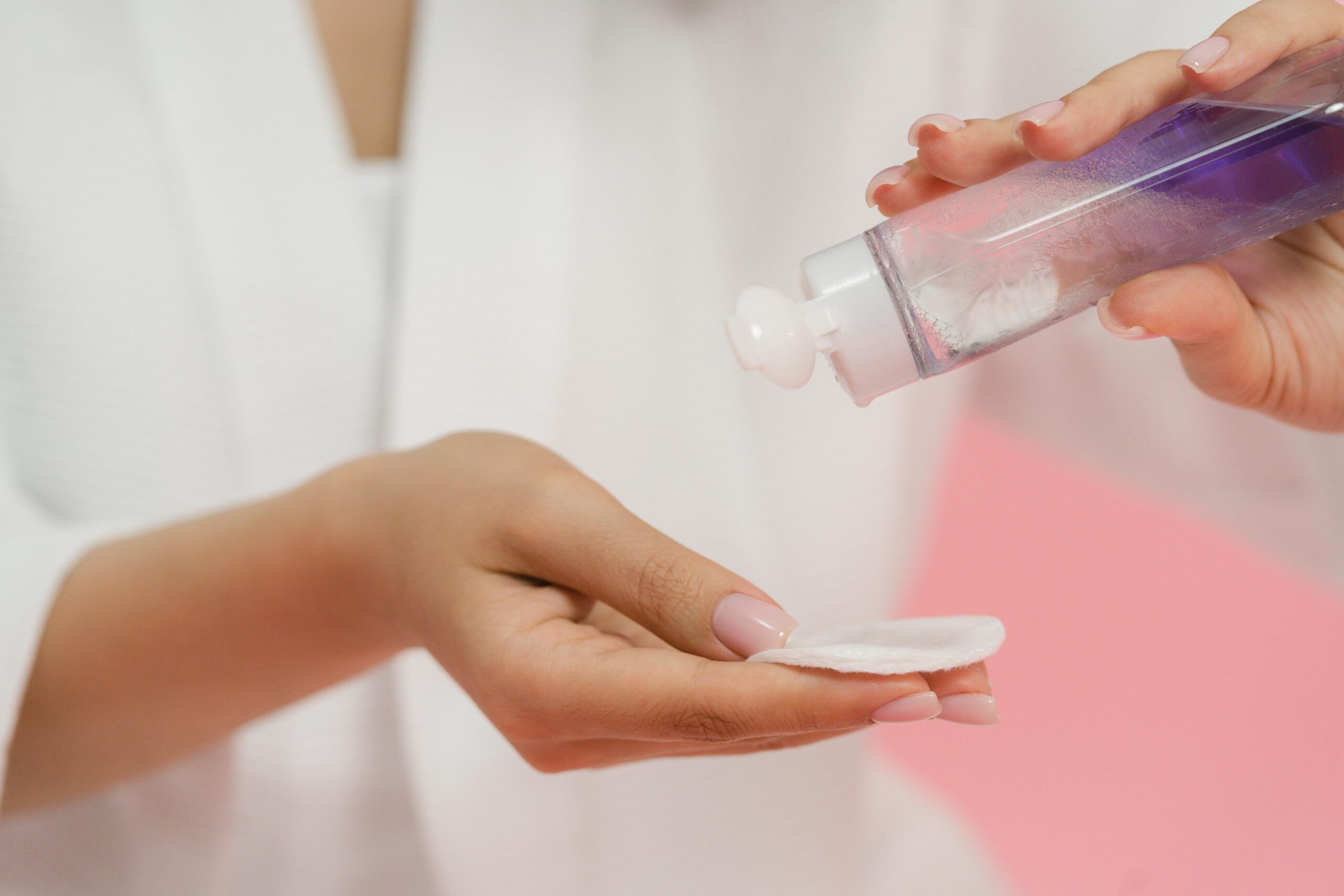 a woman's hand pouring a product in a cotton